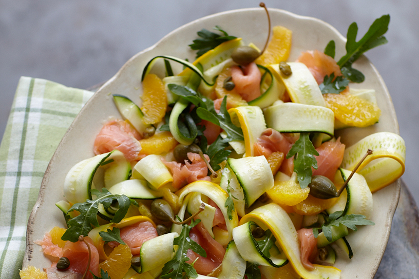 Een salade op een schaal met courgette en gerookte zalm